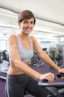 Smiling brunette working out on the cross trainer