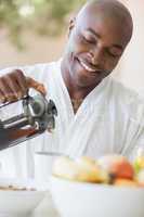 Happy man in bathrobe pouring coffee on terrace