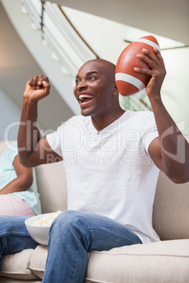 Bored woman sitting next to her boyfriend watching sport