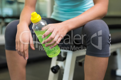 Fit woman sitting on bench holding energy drink