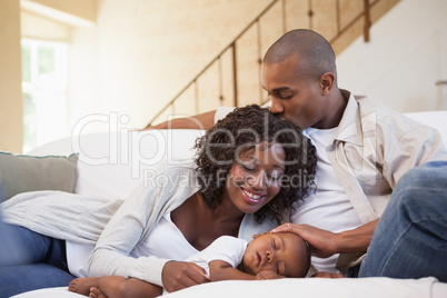 Baby boy sleeping peacefully on couch with happy parents