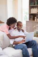 Happy couple relaxing together on the couch using laptop