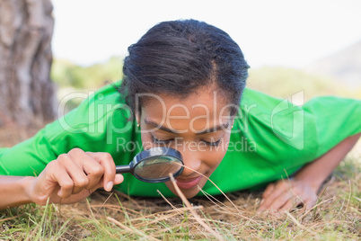 Pretty environmental activist looking at grass through magnifyin