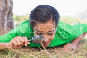 Pretty environmental activist looking at grass through magnifyin