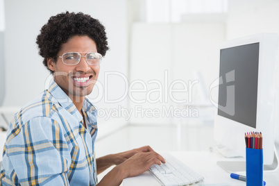 Young designer working at his desk smiling at camera