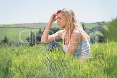 Pretty blonde thinking and sitting on grass