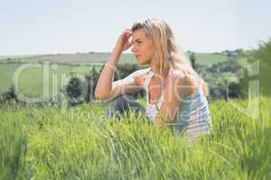 Pretty blonde thinking and sitting on grass