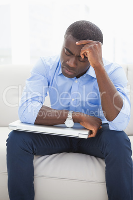 Stressed businessman getting a headache holding his laptop