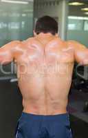 Rear view of a shirtless bodybuilder in gym