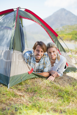 Attractive couple smiling at camera from inside their tent