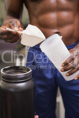 Body builder holding a scoop of protein mix