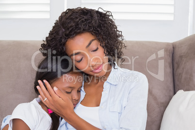 Pretty mother sitting on the couch with her sleeping daughter