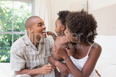 Happy couple on bed with baby daughter