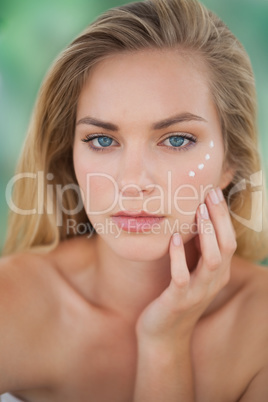 Beautiful natural blonde looking at camera with eye cream on