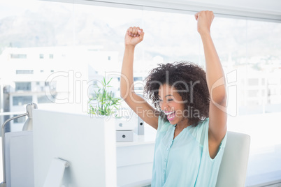 Casual businesswoman cheering at her desk Casual businesswoman cheering at her desk
