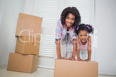 Cute daughter unpacking moving boxes with her mother