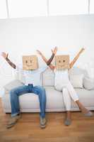 Couple sitting on couch together with boxes over head