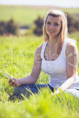 Pretty blonde sitting on grass sending a text