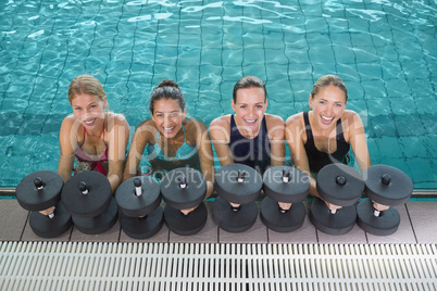 Female fitness class doing aqua aerobics with foam dumbbells