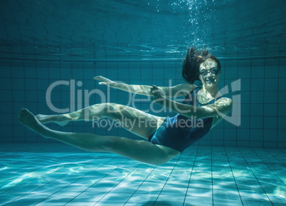 Athletic swimmer smiling at camera underwater