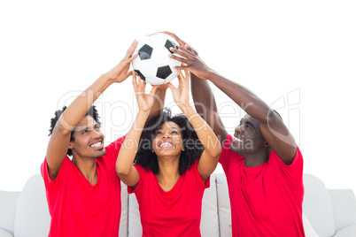 Happy football fans in red holding up ball