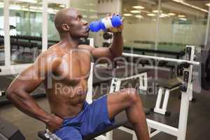 Muscular man drinking energy drink in gym