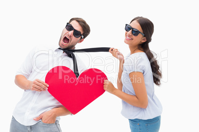 Brunette pulling her boyfriend by the tie holding heart