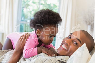 Happy father and baby girl lying on bed together