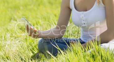 Pretty blonde sitting on grass sending a text