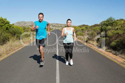 Fit couple jogging on the open road together