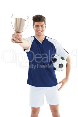 Football player in blue jersey holding winners cup