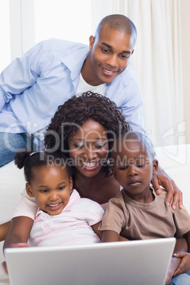 Happy family on the couch together using laptop