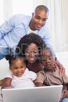 Happy family on the couch together using laptop