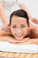 Peaceful brunette enjoying a herbal compress massage smiling at