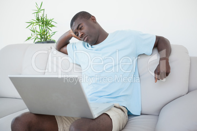 Casual man sitting on sofa using laptop