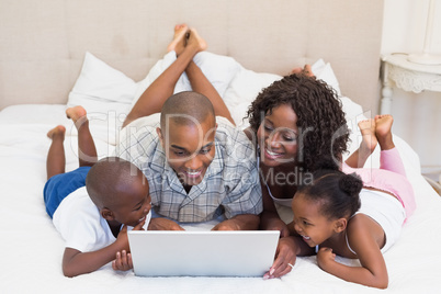 Happy family using laptop together on bed