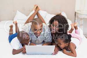 Happy family using laptop together on bed