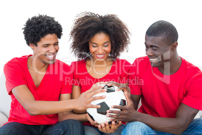 Football fans in red holding ball together