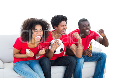 Cheering football fans in red sitting on couch