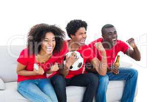 Cheering football fans in red sitting on couch