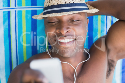 Handsome shirtless man listening to music poolside