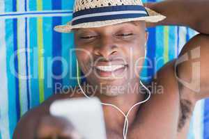 Handsome shirtless man listening to music poolside