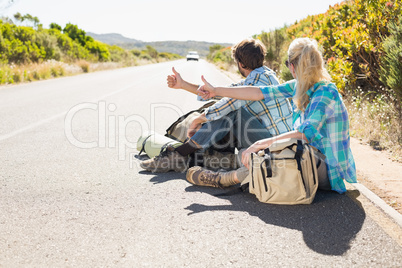 Attractive couple sitting on the road hitch hiking