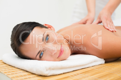 Beautiful brunette enjoying a back massage smiling at camera