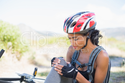 Fit woman holding her injured knee after bike crash