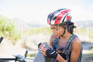 Fit woman holding her injured knee after bike crash