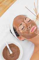 Smiling brunette getting a mud treatment facial