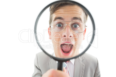 Geeky businessman looking through magnifying glass