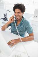 Handsome businessman talking on phone at desk