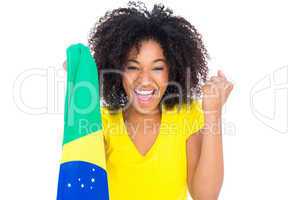 Pretty girl in yellow tshirt holding brazilian flag cheering at